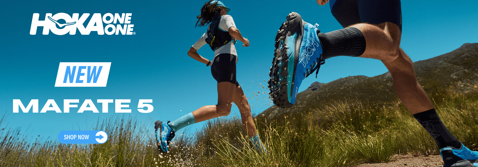 Two runners on a trail with Hoka One One Mafate 5 shoes, against a blue sky.